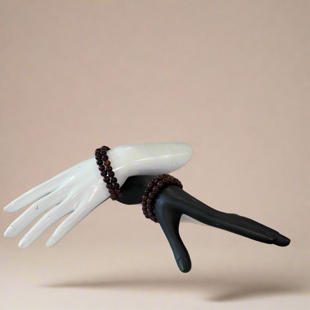 Mannequin hands with bracelets on a small round table against a neutral background